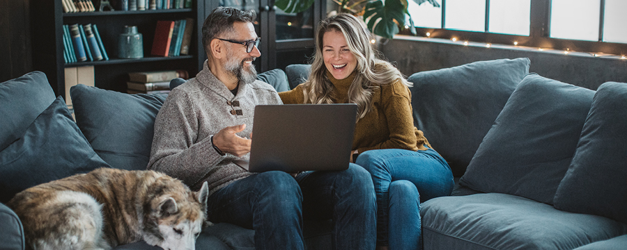 Couple sitting on couch, looking at laptop